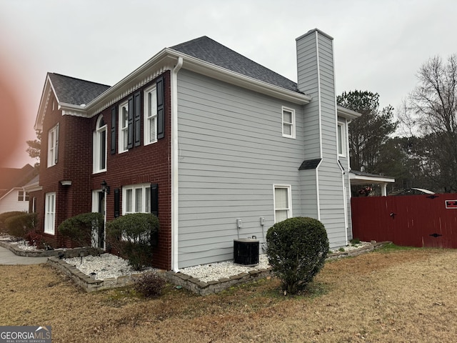 view of side of property with central AC unit and a lawn