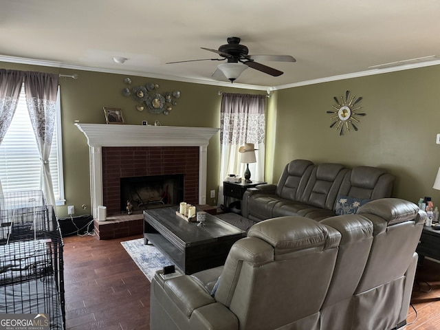 living room with crown molding, ceiling fan, dark wood-style floors, and a brick fireplace