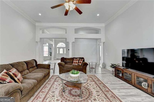 living room with ornate columns, ornamental molding, ceiling fan, and light wood-type flooring