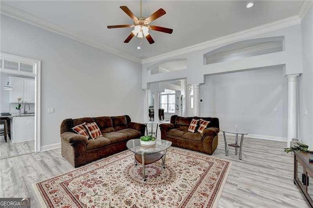 living room featuring crown molding, ceiling fan, decorative columns, and light hardwood / wood-style flooring