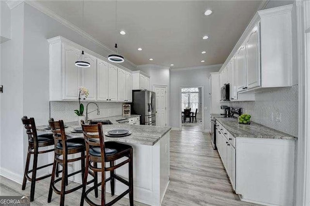 kitchen featuring sink, a breakfast bar area, white cabinetry, appliances with stainless steel finishes, and kitchen peninsula