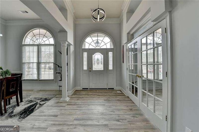 entryway with crown molding, light hardwood / wood-style floors, and decorative columns