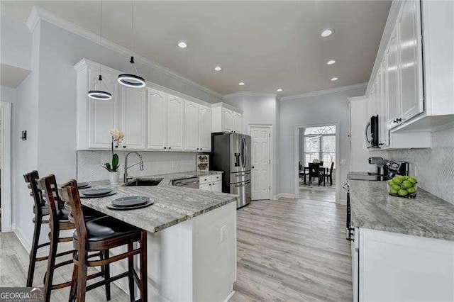 kitchen with stainless steel appliances, white cabinetry, sink, and light stone counters