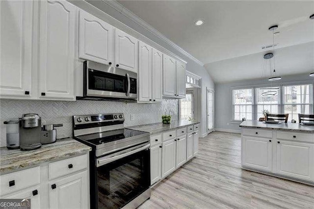 kitchen featuring appliances with stainless steel finishes, white cabinetry, lofted ceiling, backsplash, and light stone countertops