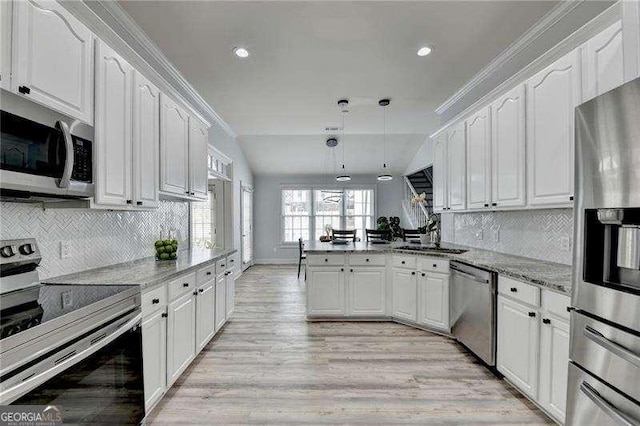 kitchen with light stone counters, kitchen peninsula, white cabinets, and appliances with stainless steel finishes