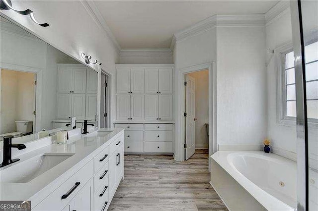 bathroom featuring a washtub, crown molding, vanity, wood-type flooring, and toilet