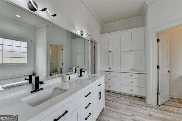 bathroom with ornamental molding, toilet, wood-type flooring, and vanity