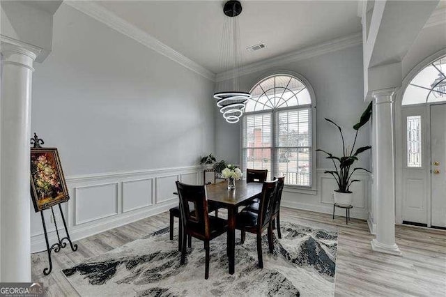 dining room featuring ornamental molding, a chandelier, light wood-type flooring, and ornate columns