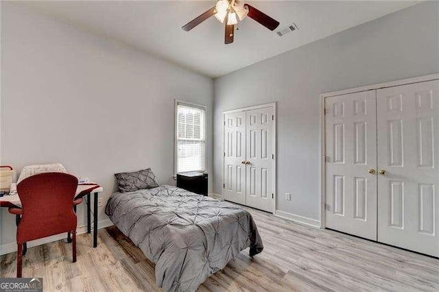 bedroom with multiple closets, ceiling fan, and light hardwood / wood-style flooring