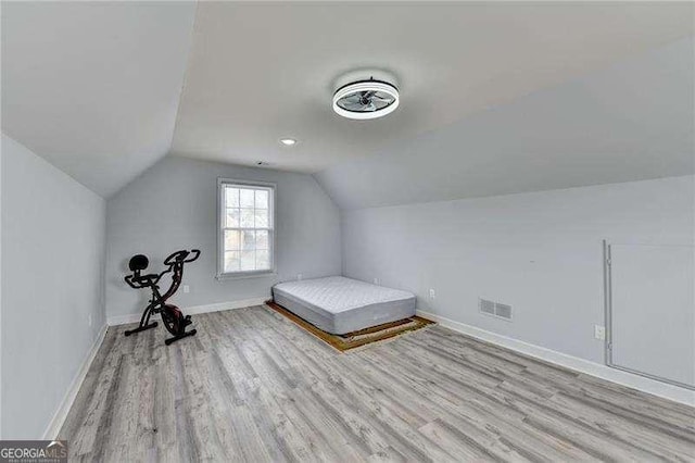 unfurnished bedroom featuring lofted ceiling and light wood-type flooring