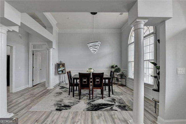 dining room featuring decorative columns, crown molding, and light hardwood / wood-style flooring