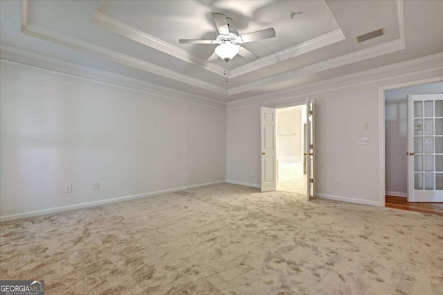 empty room featuring ceiling fan, ornamental molding, a raised ceiling, and carpet floors