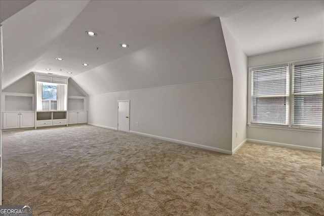 additional living space featuring lofted ceiling and carpet flooring