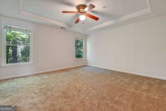 empty room featuring a tray ceiling, ornamental molding, ceiling fan, and carpet flooring