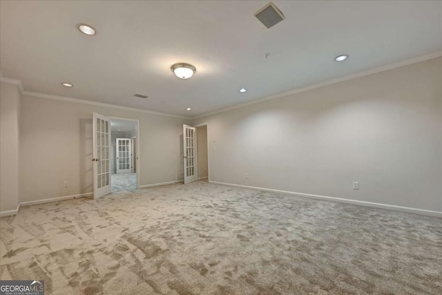 empty room with crown molding, light colored carpet, and french doors