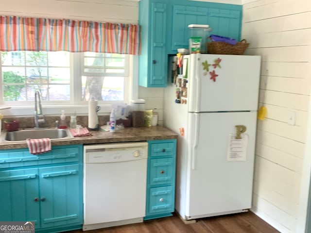 kitchen featuring sink, white appliances, dark wood-type flooring, blue cabinetry, and wooden walls