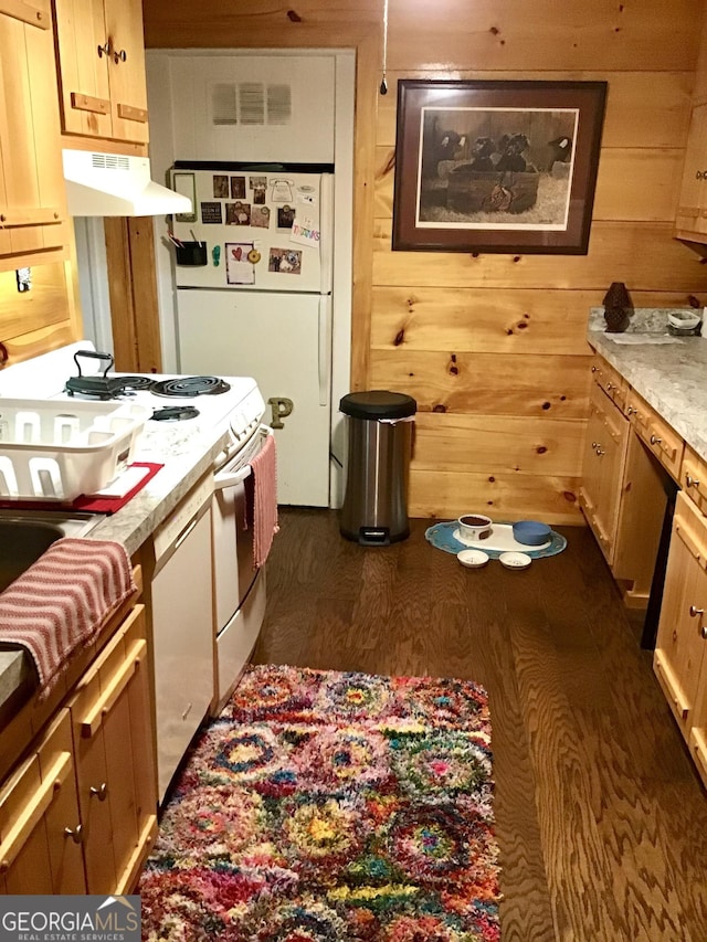 kitchen with dark hardwood / wood-style floors, white appliances, and wood walls