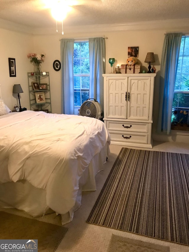 bedroom featuring crown molding, a textured ceiling, and carpet