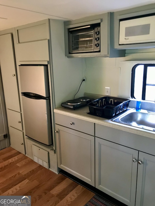 kitchen featuring dark wood-type flooring, refrigerator, sink, and gray cabinetry