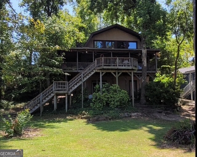 back of house with stairs, a deck, a lawn, and a gambrel roof