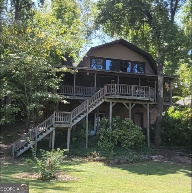 back of house with stairway, a lawn, and a wooden deck