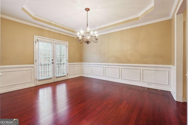 unfurnished room featuring french doors, an inviting chandelier, crown molding, a raised ceiling, and hardwood / wood-style floors