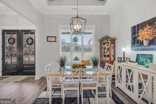 dining space with wood-type flooring, french doors, and a chandelier