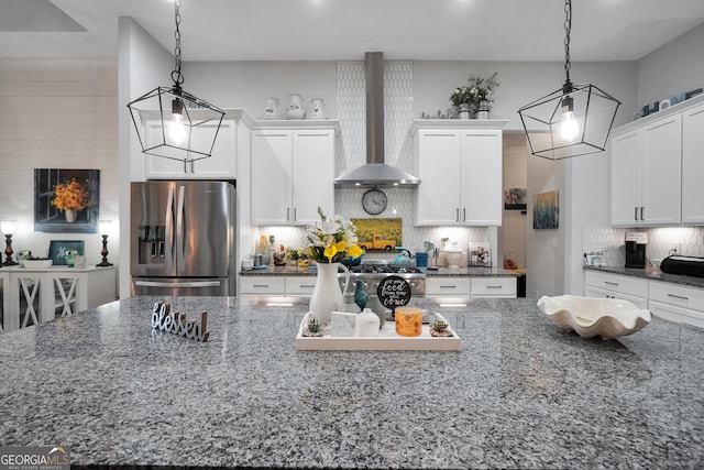 kitchen with white cabinetry, dark stone countertops, wall chimney range hood, and stainless steel fridge with ice dispenser