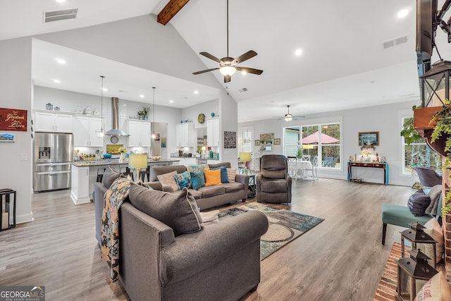 living room featuring beam ceiling, high vaulted ceiling, and light wood-type flooring