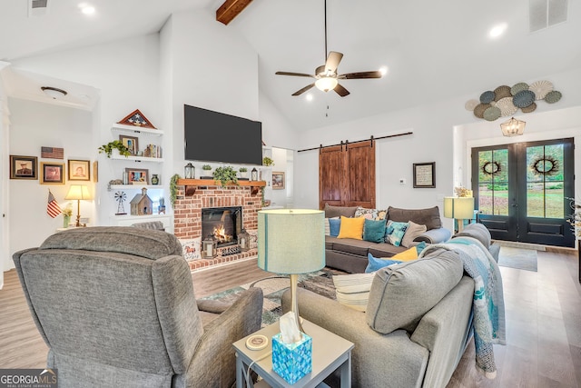 living room featuring ceiling fan, a barn door, high vaulted ceiling, and light wood-type flooring