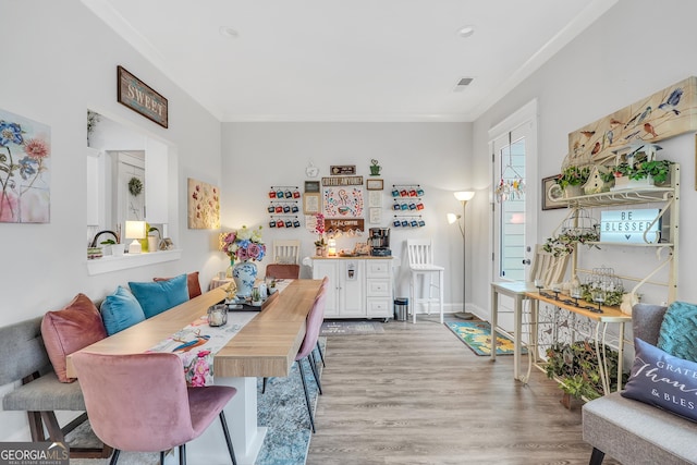 dining space with ornamental molding and light wood-type flooring