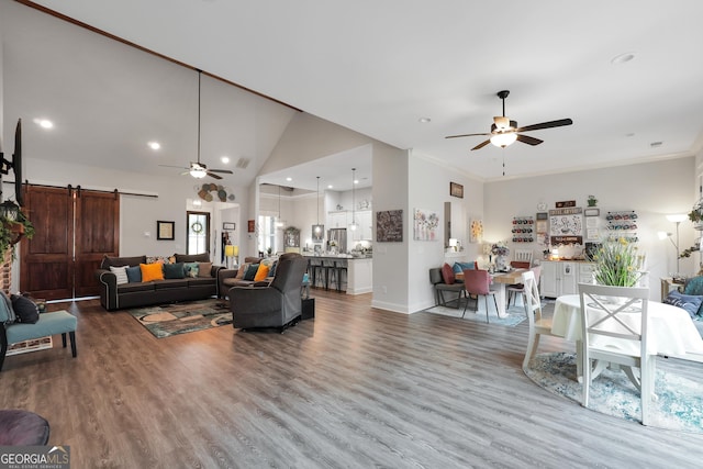 living room featuring ceiling fan, high vaulted ceiling, a barn door, and hardwood / wood-style floors