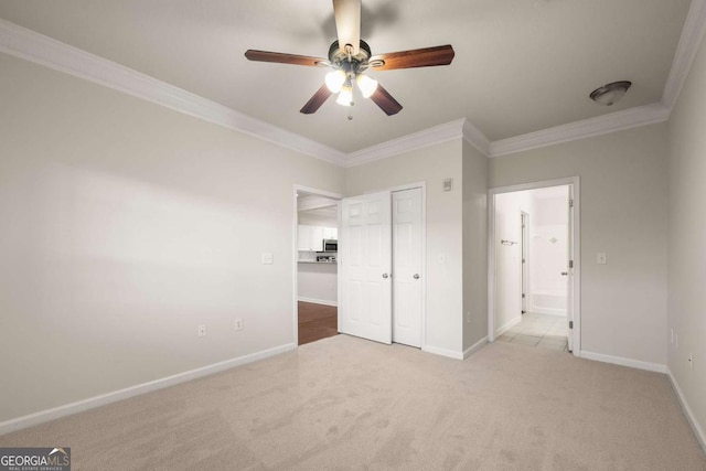 unfurnished bedroom with crown molding, light colored carpet, ceiling fan, and a closet