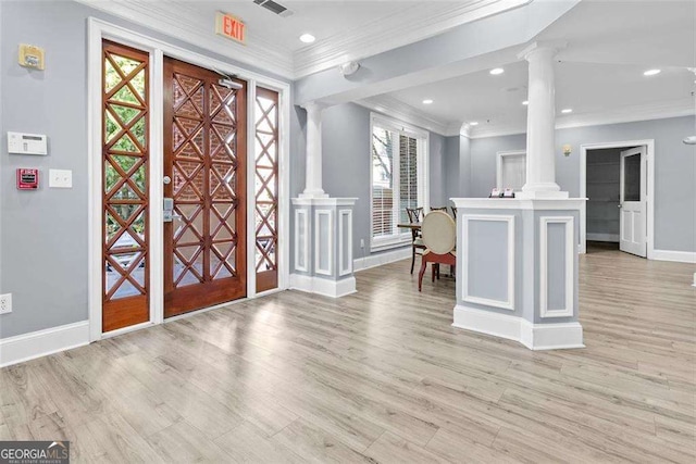 foyer entrance featuring light hardwood / wood-style flooring, ornamental molding, and ornate columns