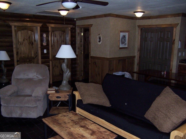 living room with dark wood-type flooring, ceiling fan, and log walls