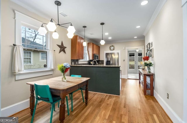 kitchen with sink, stainless steel appliances, light hardwood / wood-style floors, ornamental molding, and kitchen peninsula