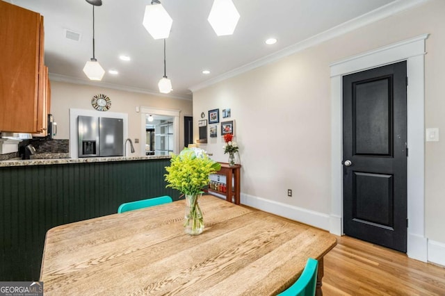 dining area featuring ornamental molding and light wood-type flooring