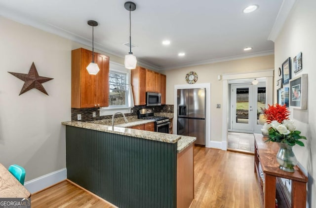 kitchen featuring light hardwood / wood-style flooring, hanging light fixtures, backsplash, stainless steel appliances, and kitchen peninsula