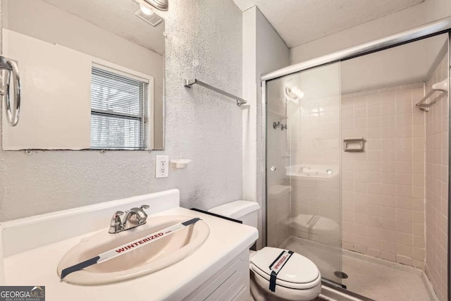 bathroom with vanity, toilet, an enclosed shower, and a textured ceiling