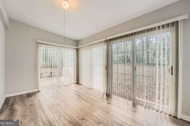 unfurnished dining area with lofted ceiling and hardwood / wood-style flooring