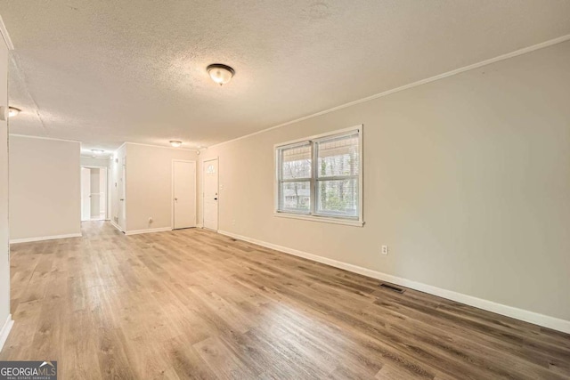 spare room with crown molding, wood-type flooring, and a textured ceiling