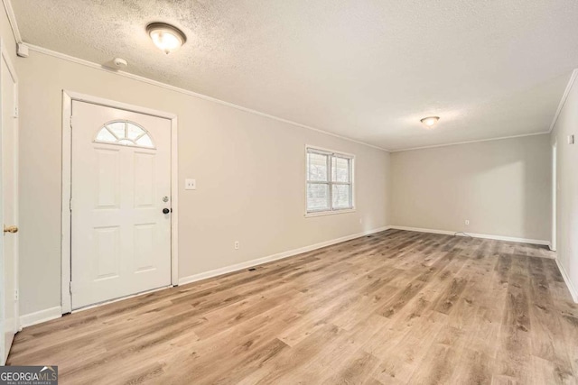 foyer featuring ornamental molding, light hardwood / wood-style flooring, and a textured ceiling