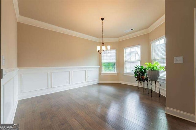 unfurnished dining area with dark hardwood / wood-style flooring, crown molding, and an inviting chandelier