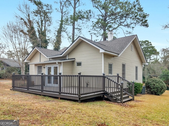 rear view of property featuring a wooden deck, a lawn, and french doors