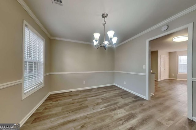 empty room featuring crown molding, a chandelier, and hardwood / wood-style flooring