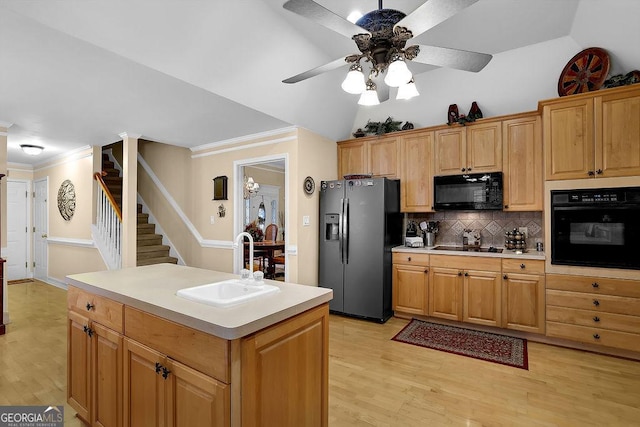 kitchen featuring a kitchen island with sink, sink, vaulted ceiling, and black appliances