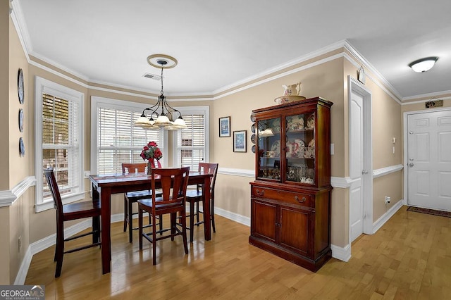 dining space featuring ornamental molding and light hardwood / wood-style floors