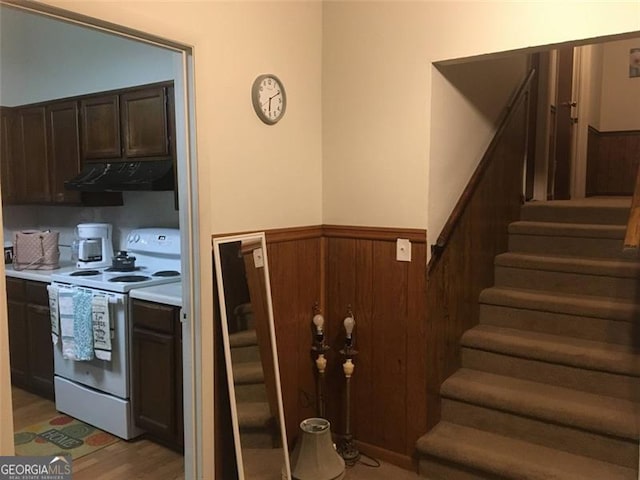 kitchen featuring white electric stove, light hardwood / wood-style flooring, and wood walls