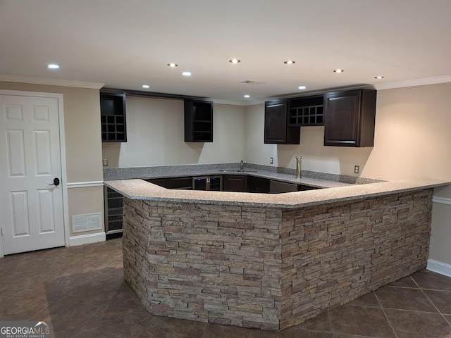 bar with ornamental molding, dark tile patterned flooring, and sink