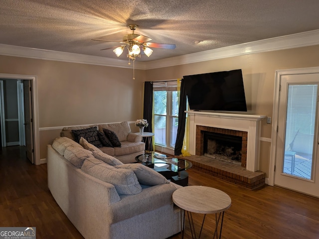 living room featuring a brick fireplace, crown molding, dark wood-type flooring, and a textured ceiling